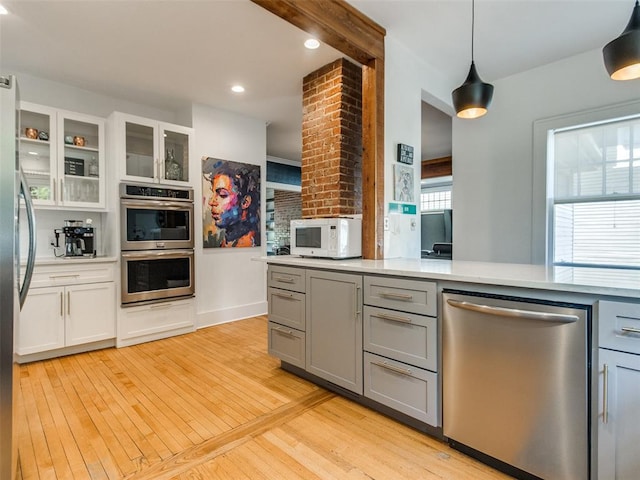 1218 NW 21st St, Oklahoma City, OK 73106 - kitchen featuring appliances with stainless steel finishes, gray cabinetry, light wood-type flooring, light countertops, and glass insert cabinets