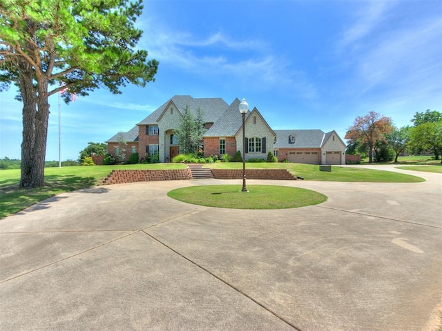 12940 E Reno Ave, Choctaw, OK 73020 - french provincial home featuring curved driveway, a front yard, brick siding, and a garage