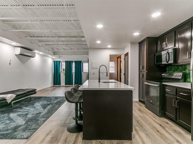 931 NW 7th St Unit 104, Oklahoma City, OK 73106 - kitchen featuring stainless steel microwave, electric range, open floor plan, a wall mounted AC, and light countertops
