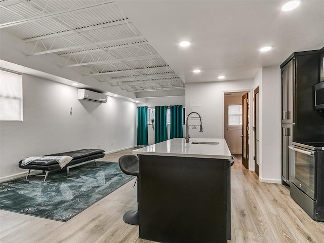 931 NW 7th St Unit 104, Oklahoma City, OK 73106 - kitchen with a wall unit AC, light wood-type flooring, stainless steel appliances, light countertops, and recessed lighting
