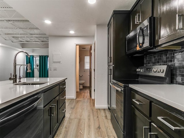 931 NW 7th St Unit 104, Oklahoma City, OK 73106 - kitchen with appliances with stainless steel finishes, light wood-type flooring, light countertops, dark cabinetry, and recessed lighting