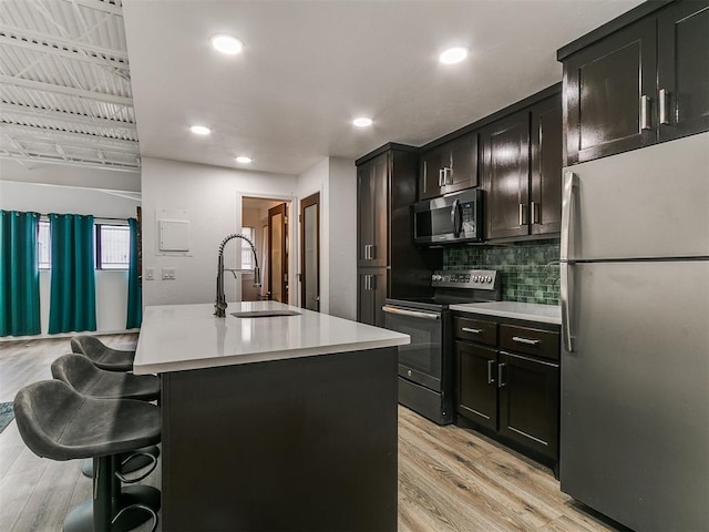 931 NW 7th St Unit 104, Oklahoma City, OK 73106 - kitchen with appliances with stainless steel finishes, a breakfast bar area, light countertops, light wood-style flooring, and backsplash