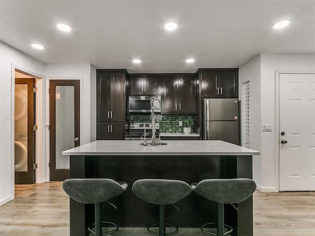 931 NW 7th St Unit 104, Oklahoma City, OK 73106 - kitchen with stainless steel appliances, light wood-style floors, light countertops, backsplash, and recessed lighting