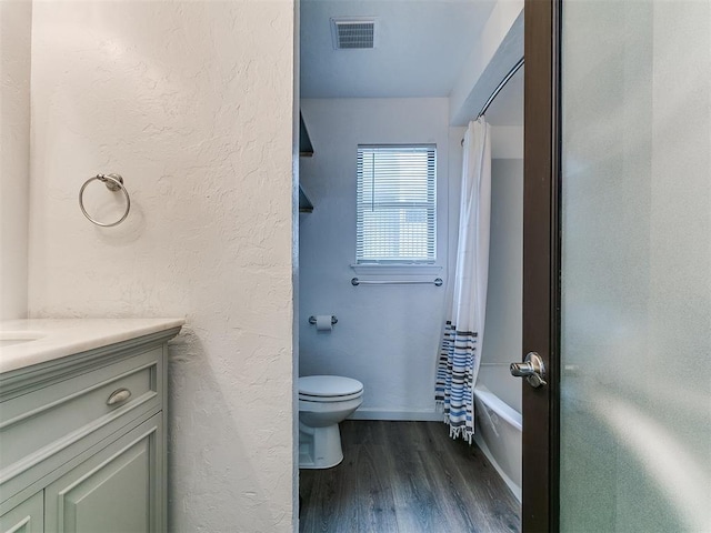 931 NW 7th St Unit 104, Oklahoma City, OK 73106 - bathroom with wood finished floors, vanity, shower / bath combo with shower curtain, and a textured wall