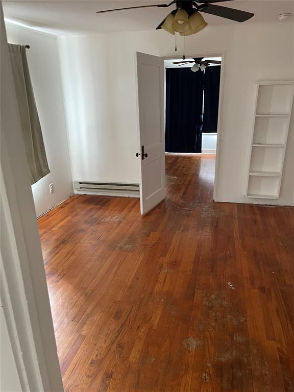 128 W Ridgewood St, Shawnee, OK 74801 - empty room with baseboard heating, a ceiling fan, hardwood / wood-style flooring, and a smoke detector