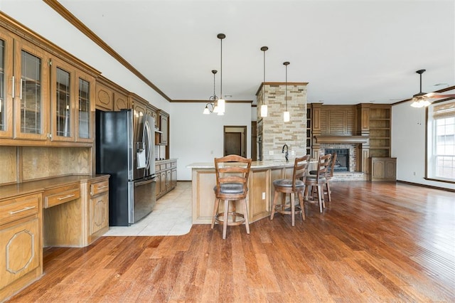 2613 NW 159th St, Edmond, OK 73013 - kitchen featuring stainless steel fridge with ice dispenser, light wood-style floors, a kitchen breakfast bar, crown molding, and glass insert cabinets