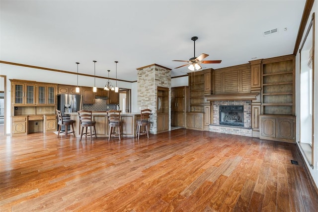 2613 NW 159th St, Edmond, OK 73013 - living area featuring a ceiling fan, crown molding, a fireplace, and light wood-type flooring