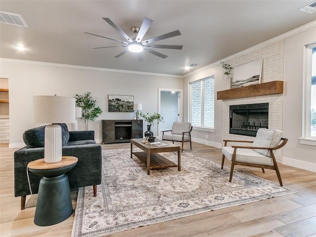 12825 Painted Sky, Edmond, OK 73007 - living room featuring a fireplace, crown molding, light wood finished floors, ceiling fan, and baseboards