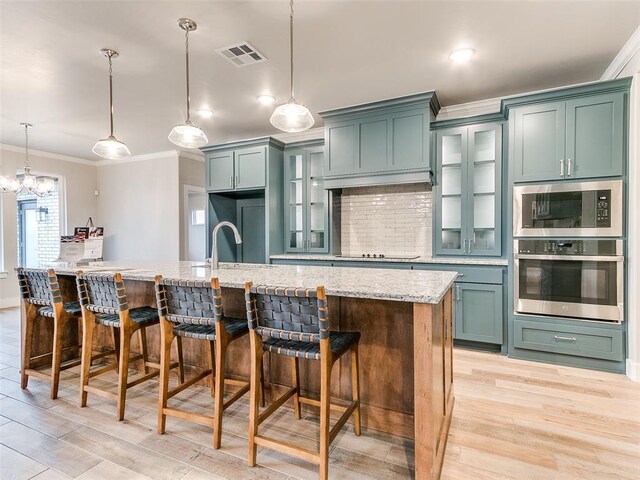 12825 Painted Sky, Edmond, OK 73007 - kitchen with stainless steel appliances, crown molding, light stone counters, light wood-style flooring, and decorative light fixtures