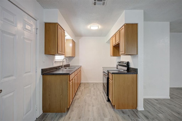 1633 SE 52nd St, Oklahoma City, OK 73129 - kitchen with stainless steel range with electric cooktop, dark countertops, light wood-style flooring, a textured ceiling, and a sink