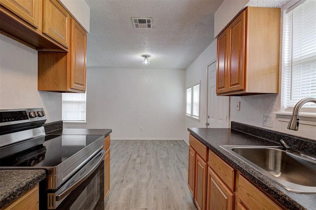 1633 SE 52nd St, Oklahoma City, OK 73129 - kitchen with electric range, a sink, dark countertops, light wood-type flooring, and a textured ceiling