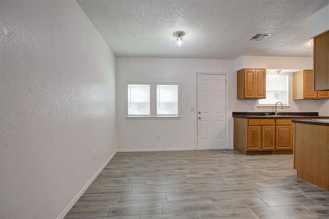 1633 SE 52nd St, Oklahoma City, OK 73129 - kitchen with dark countertops, a textured ceiling, a textured wall, baseboards, and brown cabinets