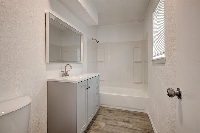 1633 SE 52nd St, Oklahoma City, OK 73129 - bathroom with a textured wall, vanity, toilet, wood finished floors, and shower / bathtub combination