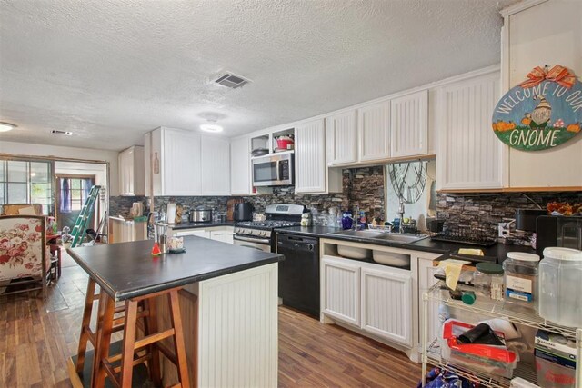 1001 N Pine St, Midwest City, OK 73130 - kitchen featuring stainless steel appliances, dark countertops, a sink, decorative backsplash, and a textured ceiling