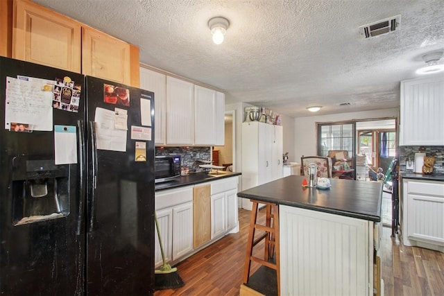 1001 N Pine St, Midwest City, OK 73130 - kitchen featuring fridge with ice dispenser, dark countertops, tasteful backsplash, a textured ceiling, and wood finished floors