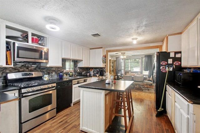 1001 N Pine St, Midwest City, OK 73130 - kitchen featuring black appliances, dark countertops, a sink, a kitchen island, and light wood-style flooring