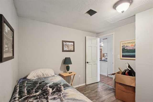 1001 N Pine St, Midwest City, OK 73130 - bedroom with wood finished floors, a textured ceiling, and baseboards
