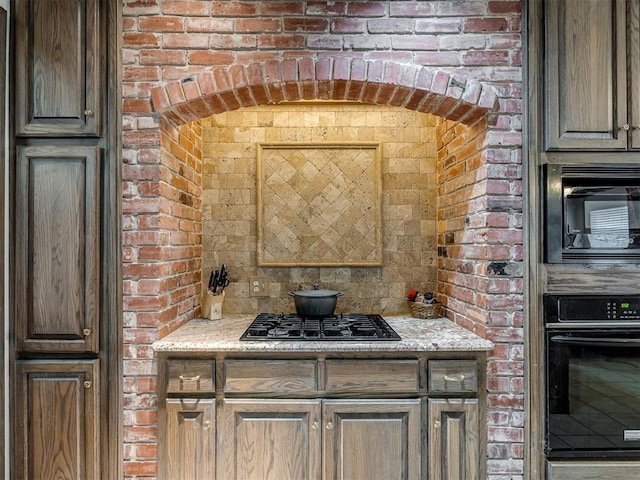 2500 Huntwick Dr, Edmond, OK 73034 - kitchen featuring black appliances, brick wall, and light stone countertops