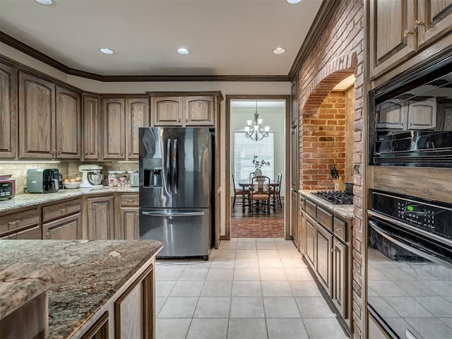 2500 Huntwick Dr, Edmond, OK 73034 - kitchen with black appliances, a chandelier, light stone counters, decorative backsplash, and crown molding