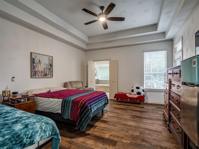 2500 Huntwick Dr, Edmond, OK 73034 - bedroom featuring dark wood-style floors, a raised ceiling, refrigerator, ensuite bath, and ceiling fan
