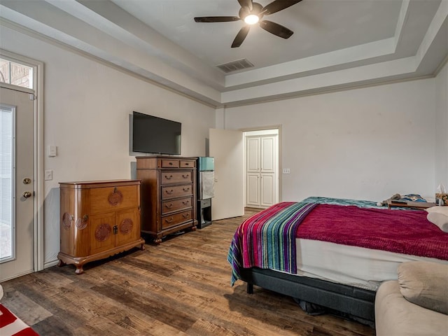 2500 Huntwick Dr, Edmond, OK 73034 - bedroom featuring wood finished floors, a tray ceiling, and a ceiling fan
