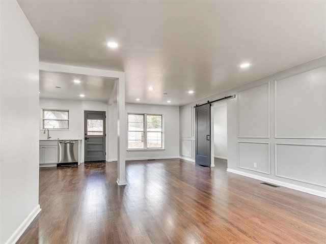 1224 W Brooks St, Norman, OK 73069 - unfurnished living room with a barn door, dark wood-style flooring, recessed lighting, baseboards, and a sink