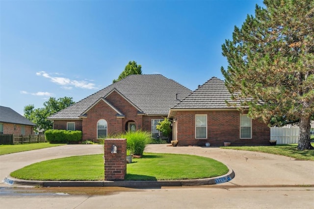 11700 Hackney Ln, Yukon, OK 73099 - traditional-style house featuring brick siding, a tile roof, and curved driveway