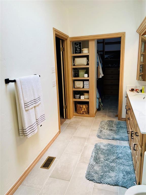 11700 Hackney Ln, Yukon, OK 73099 - bathroom featuring vanity, a walk in closet, tile patterned floors, and baseboards