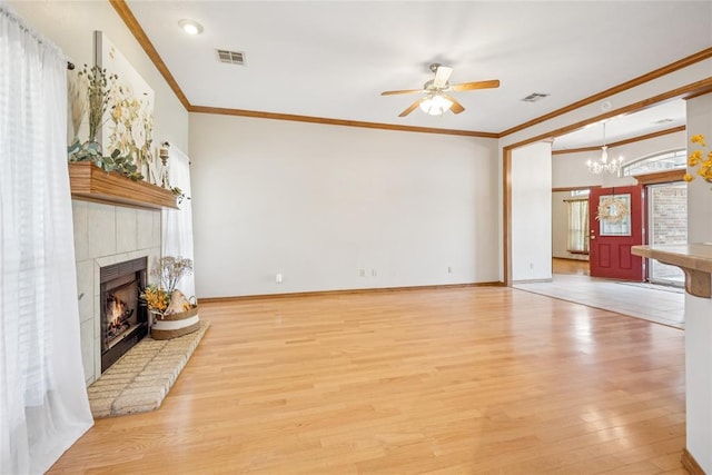 1908 Riviera Dr, Tuttle, OK 73089 - unfurnished living room featuring crown molding, a lit fireplace, a ceiling fan, a chandelier, and light wood-style flooring