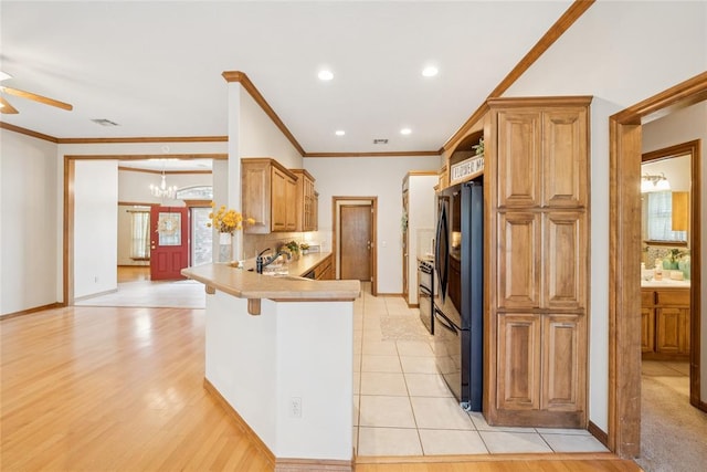 1908 Riviera Dr, Tuttle, OK 73089 - kitchen featuring freestanding refrigerator, a peninsula, a chandelier, ceiling fan, and a kitchen breakfast bar