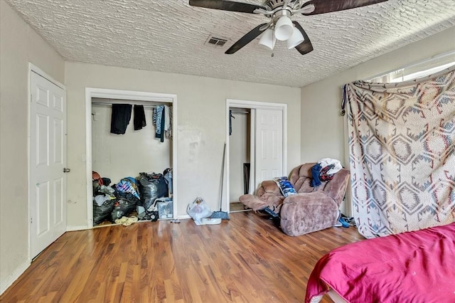 208 E Lockheed Dr, Midwest City, OK 73110 - bedroom featuring two closets, wood finished floors, a ceiling fan, and a textured ceiling