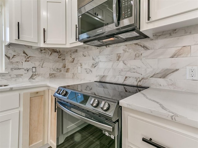 26603 Main St, Blanchard, OK 73010 - kitchen with stainless steel electric stove, decorative backsplash, white cabinetry, and light stone counters