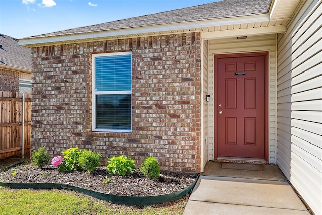 11604 NW 95th St, Yukon, OK 73099 - view of exterior entry featuring brick siding and a shingled roof