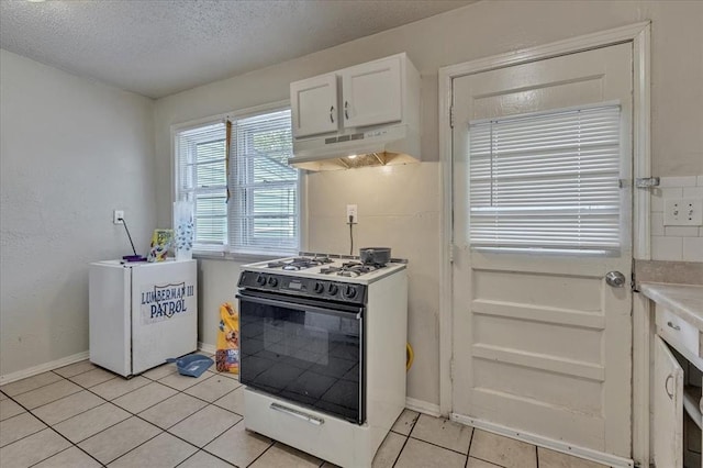 1500 Maple Dr, Midwest City, OK 73110 - kitchen featuring white gas stove, under cabinet range hood, light tile patterned flooring, white cabinetry, and a textured ceiling