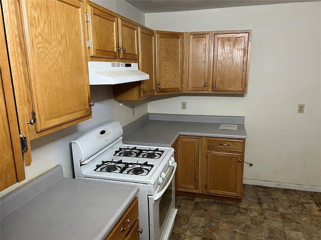 1012 Box St, Altus, OK 73521 - kitchen featuring white range with gas cooktop, under cabinet range hood, brown cabinetry, and light countertops