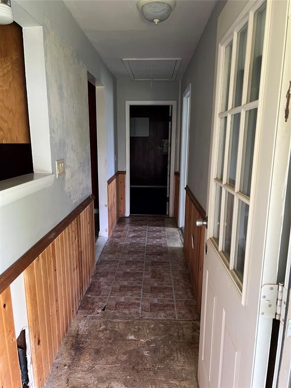 1012 Box St, Altus, OK 73521 - hallway featuring attic access, a wainscoted wall, and dark stone finish floors