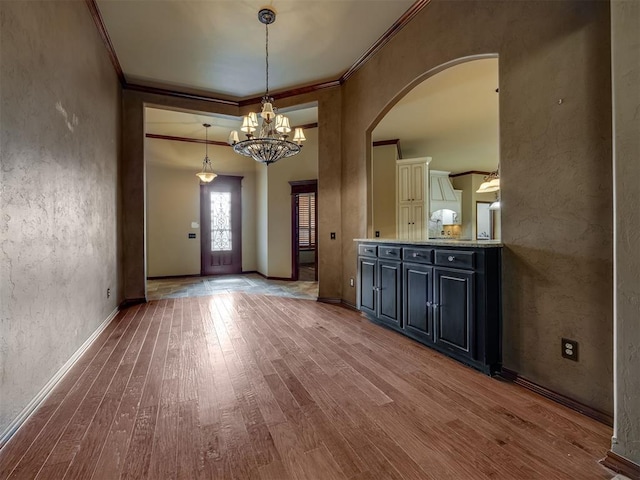 3605 SW Wayfield Ave, Oklahoma City, OK 73132 - unfurnished dining area featuring arched walkways, wood finished floors, crown molding, a chandelier, and baseboards