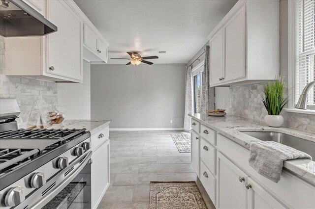 724 SW 48th St, Oklahoma City, OK 73109 - kitchen featuring stainless steel gas stove, under cabinet range hood, ceiling fan, white cabinets, and decorative backsplash