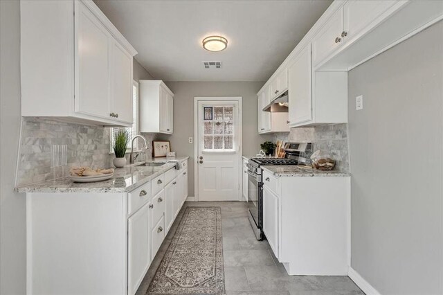 724 SW 48th St, Oklahoma City, OK 73109 - kitchen with stainless steel gas range oven, backsplash, light stone counters, and white cabinetry
