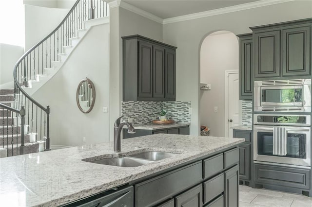 1417 Cordgrass Ct, Edmond, OK 73013 - kitchen featuring appliances with stainless steel finishes, a sink, tasteful backsplash, light stone countertops, and arched walkways