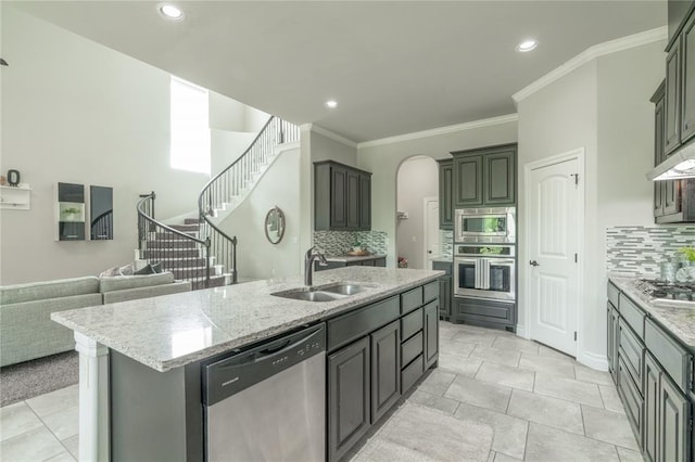 1417 Cordgrass Ct, Edmond, OK 73013 - kitchen with appliances with stainless steel finishes, a sink, a center island with sink, decorative backsplash, and arched walkways