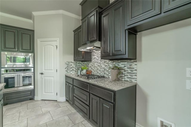1417 Cordgrass Ct, Edmond, OK 73013 - kitchen with appliances with stainless steel finishes, backsplash, under cabinet range hood, ornamental molding, and light stone counters