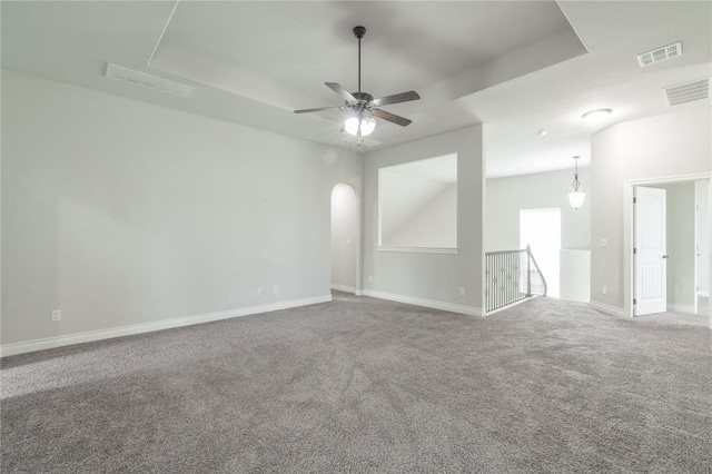 1417 Cordgrass Ct, Edmond, OK 73013 - carpeted empty room featuring a ceiling fan, a tray ceiling, baseboards, and arched walkways