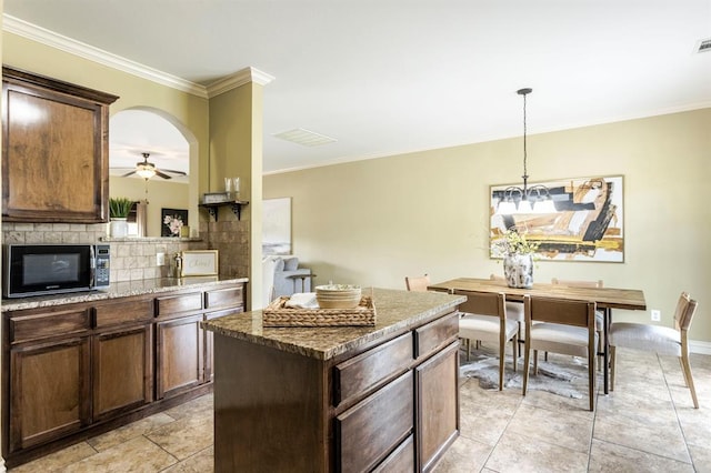 17504 Silverhawk Way, Edmond, OK 73012 - kitchen featuring black microwave, ornamental molding, stone countertops, a kitchen island, and a ceiling fan