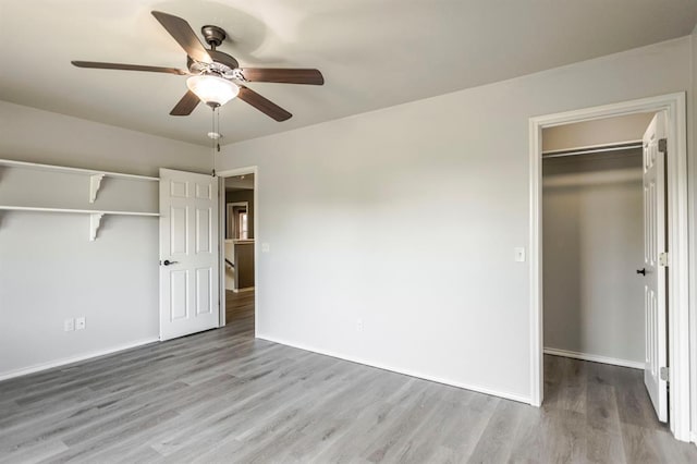 17504 Silverhawk Way, Edmond, OK 73012 - unfurnished bedroom featuring wood finished floors, a closet, baseboards, and a walk in closet