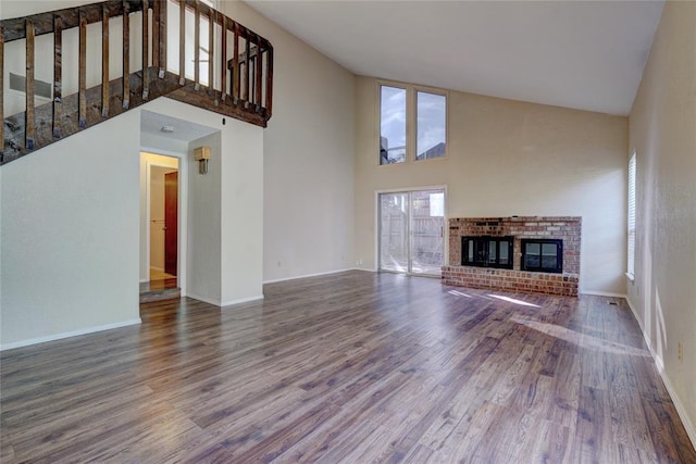12217 Cork Rd, Oklahoma City, OK 73162 - unfurnished living room with a towering ceiling, wood finished floors, a fireplace, and stairs
