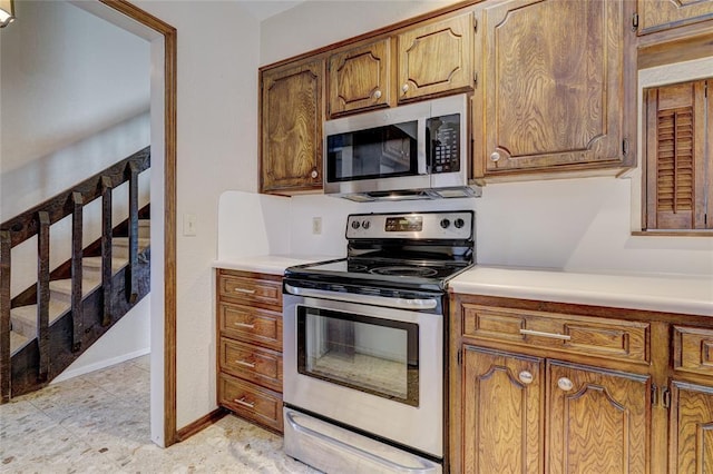 12217 Cork Rd, Oklahoma City, OK 73162 - kitchen featuring stainless steel appliances, light countertops, and brown cabinetry