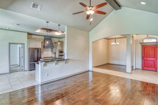 3024 Wakefield Rd, Edmond, OK 73034 - kitchen with stainless steel appliances, arched walkways, custom exhaust hood, light wood-style floors, and beamed ceiling