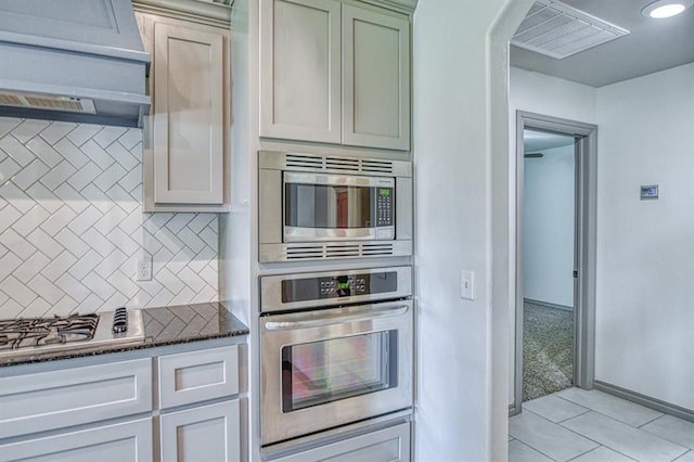 3024 Wakefield Rd, Edmond, OK 73034 - kitchen featuring stainless steel appliances, tasteful backsplash, extractor fan, dark stone counters, and light tile patterned flooring