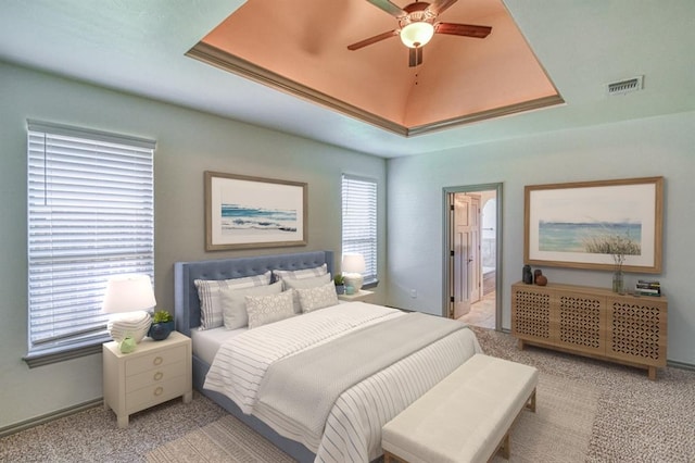 3024 Wakefield Rd, Edmond, OK 73034 - bedroom featuring a tray ceiling, light carpet, ensuite bathroom, and a ceiling fan